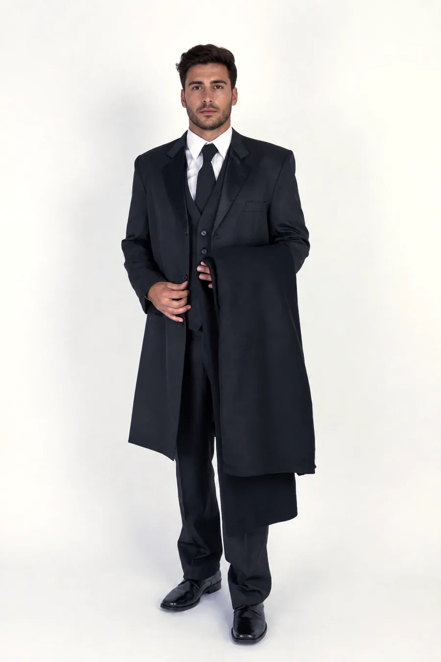 Estudante com o traje académico completo do Porto: batina, colete, calças, camisa branca, gravata preta e a capa dobrada ao braço.